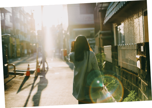 Rear view of woman leaving home to work in the early morning against warm sunlight